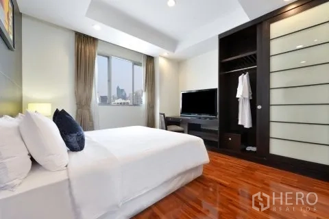 อพาร์ทเมนท์ for rent in Watthana, Bangkok - ห้องนอนอบอุ่นพร้อมหน้าต่างบานใหญ่ ชั้นวางทีวี และตู้เสื้อผ้าบานเลื่อน