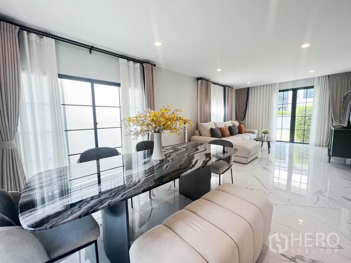 Detached House for rent in Khan Na Yao, Bangkok - Open-plan living and dining area featuring a glossy black marble table and wide windows with layered curtains.