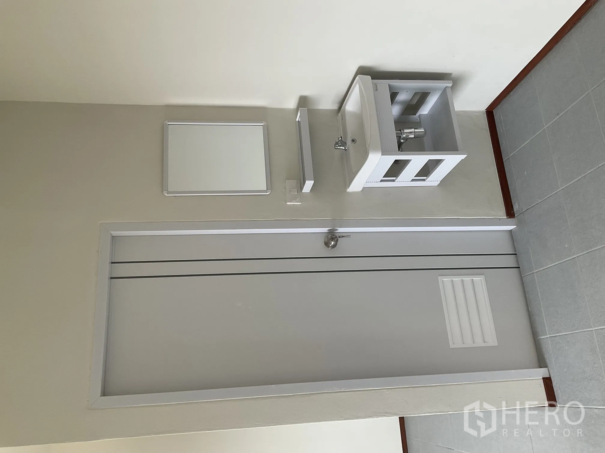 Warehouse for rent in Lat Lum Kaeo, Pathum Thani - Compact washbasin with mirror beside an interior door in a tiled area.