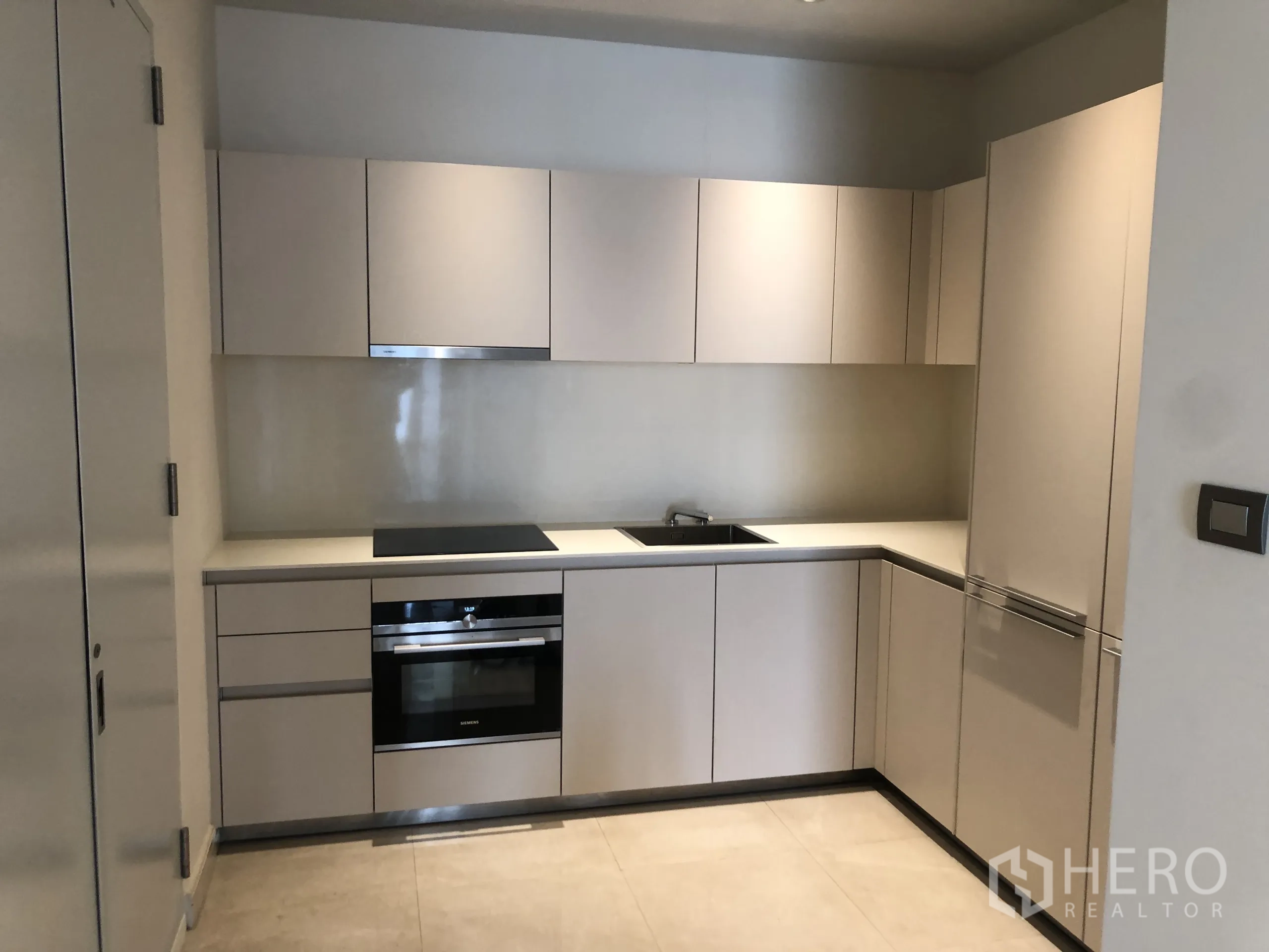 公寓 出租在Pathum Wan, Bangkok - 当代L型厨房，配嵌入式电磁炉、烤箱与隐藏式冰箱。