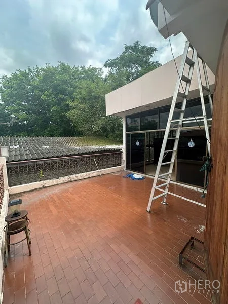 Detached House for sale in Phra Khanong, Bangkok - Rooftop terrace with red tiles, a ladder and a glass-enclosed room, surrounded by greenery.