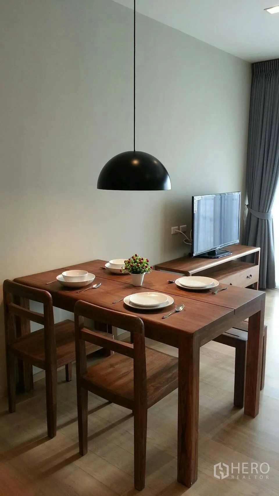 Condominium for rent or sale in Watthana, Bangkok - Dining table for four under a black pendant lamp beside TV console and floor‑to‑ceiling curtains.