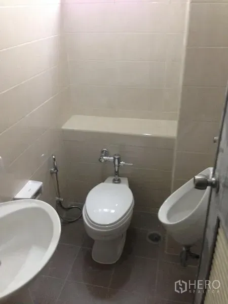 Office Space for rent in Bang Kapi, Bangkok - Compact restroom with toilet, urinal, sink and neutral tiled walls.