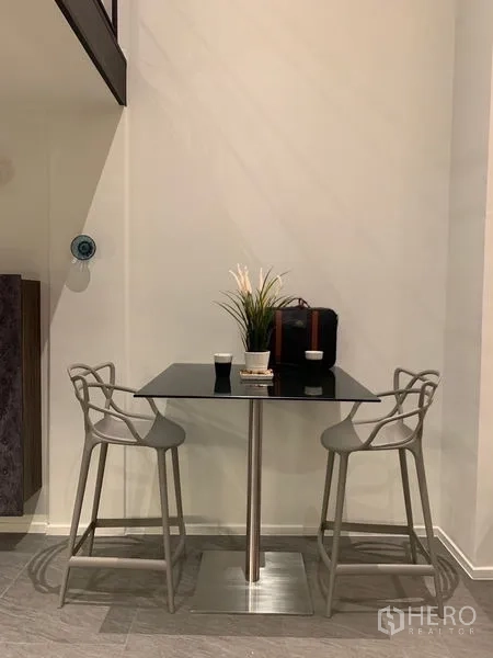 Condominium for rent in Bang Rak, Bangkok - Compact dining nook with glass-top table and two designer chairs.
