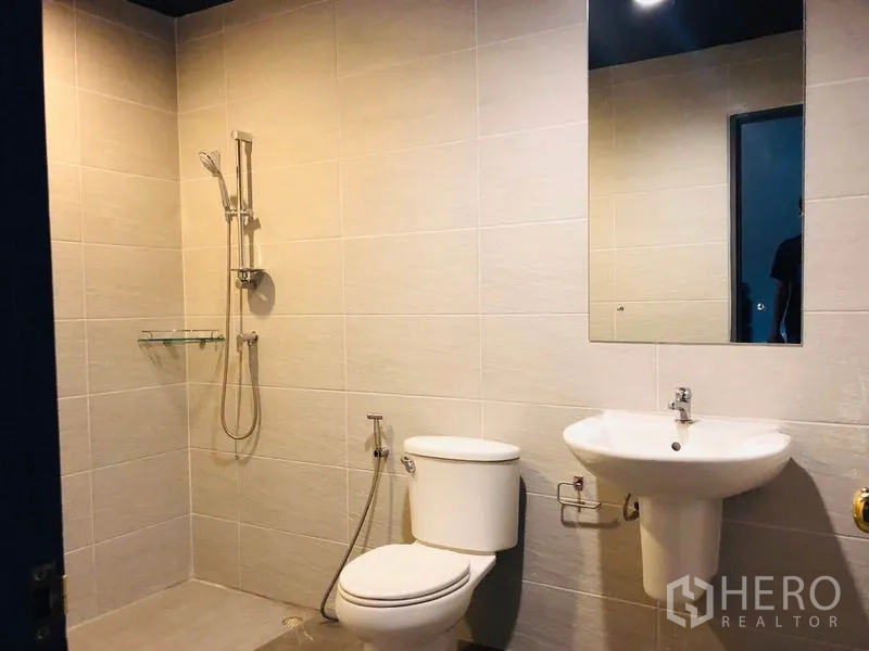 Townhouse for rent in Bang Kapi, Bangkok - Clean bathroom with walk-in shower, toilet, pedestal sink and large mirror.