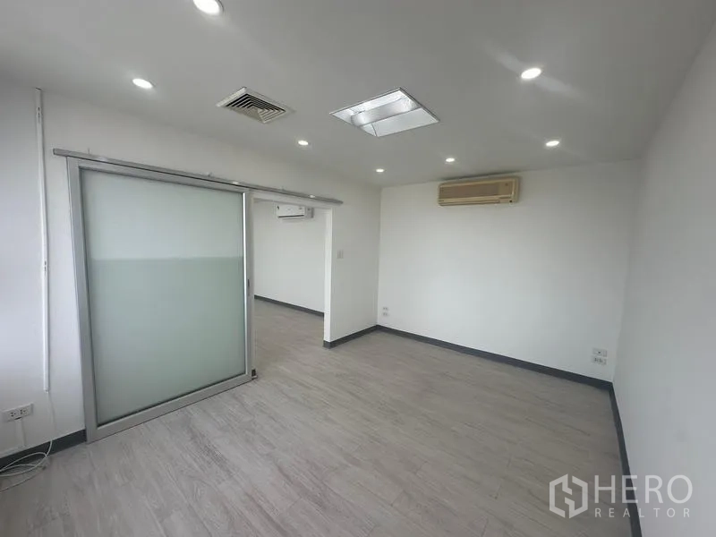 Office Space for rent - Compact office area with a frosted sliding glass partition and wall-mounted air conditioner.