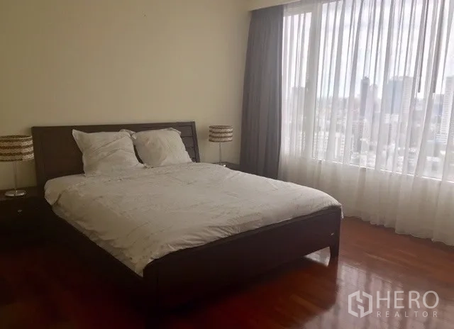 Condominium for rent in Watthana, Bangkok - Primary bedroom with wood flooring and large window overlooking the city.