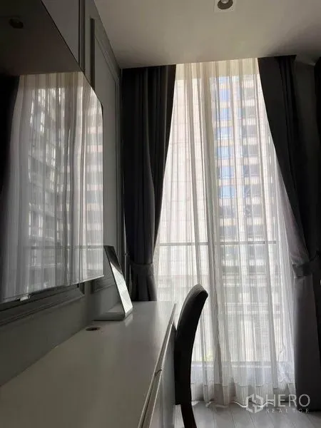 公寓 出租在Pathum Wan, Bangkok - 落地窗旁的书桌与椅子，纱帘与遮光帘，城市景观