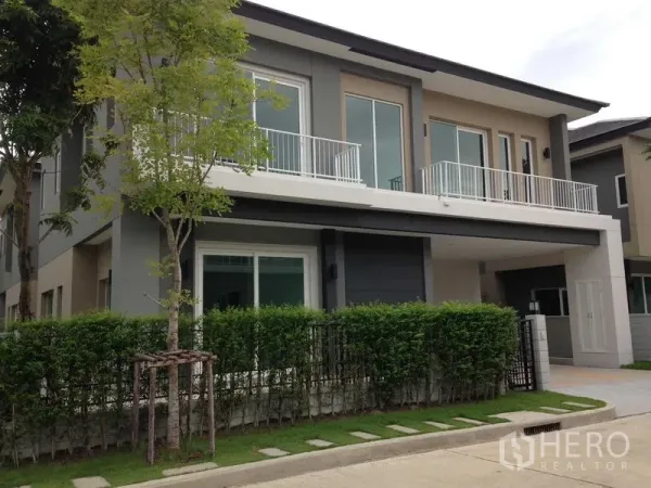 บ้าน ให้เช่าหรือขายในBang Na, Bangkok - บ้านเดี่ยวสองชั้นสไตล์โมเดิร์น มีระเบียง รั้วพุ่มไม้ และที่จอดรถ