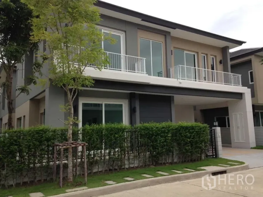 บ้าน ให้เช่าหรือขายในBang Na, Bangkok - บ้านเดี่ยวสองชั้นสไตล์โมเดิร์น มีระเบียง รั้วพุ่มไม้ และที่จอดรถ
