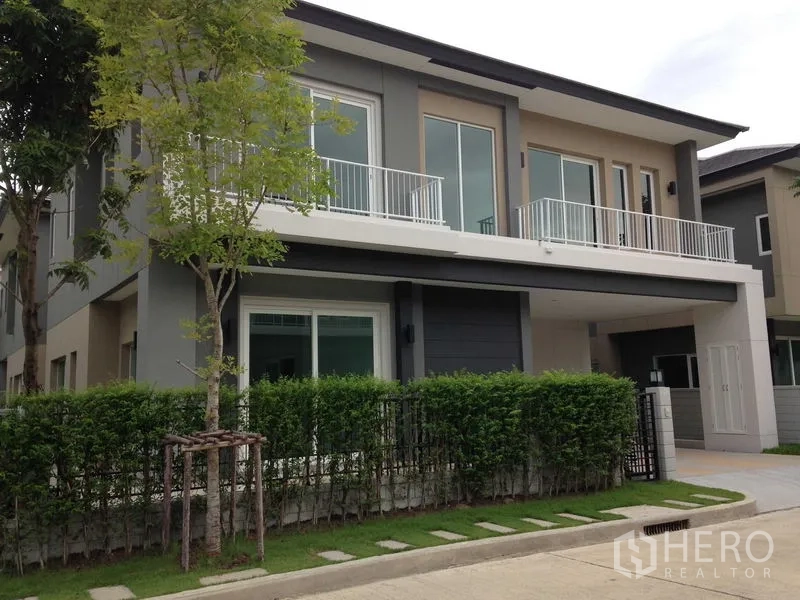 บ้าน ให้เช่าหรือขายในBang Na, Bangkok - บ้านเดี่ยวสองชั้นสไตล์โมเดิร์น มีระเบียง รั้วพุ่มไม้ และที่จอดรถ
