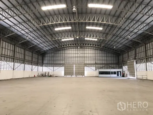 货栈 出租在Pathum Thani - 高挑无柱仓库内部，拱形钢桁架屋顶与平整混凝土地面。