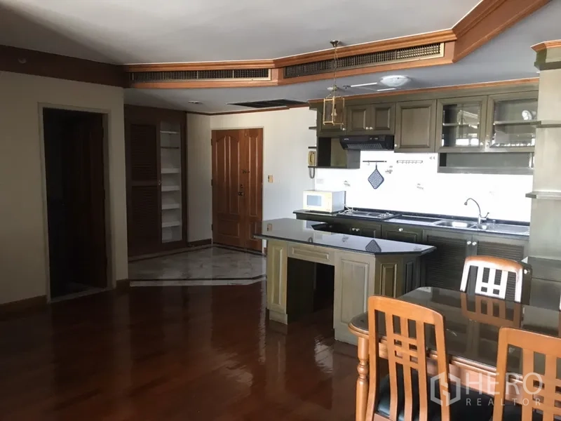 公寓 出租在Watthana, Bangkok - 开放式厨房，带中岛，绿色橱柜、炉灶、水槽与微波炉。