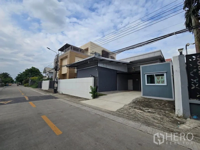货栈 出租在Don Mueang, Bangkok - 斜角视图，展示宽阔道路与通往卷闸门的混凝土车道。
