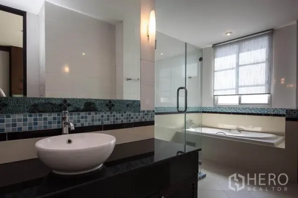 公寓 出租在Khlong Toei, Bangkok - 现代浴室，台上盆配马赛克挡水板，玻璃淋浴间与靠窗浴缸。