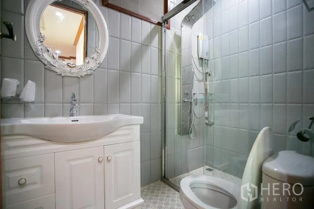 独栋房屋 for rent or sale in Huai Khwang, Bangkok - 第二卫生间，白色洗手台、装饰镜与玻璃淋浴房。