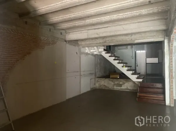 Retail Space for rent in Khlong Toei, Bangkok - Industrial-style retail space with a white floating staircase and concrete ceiling.