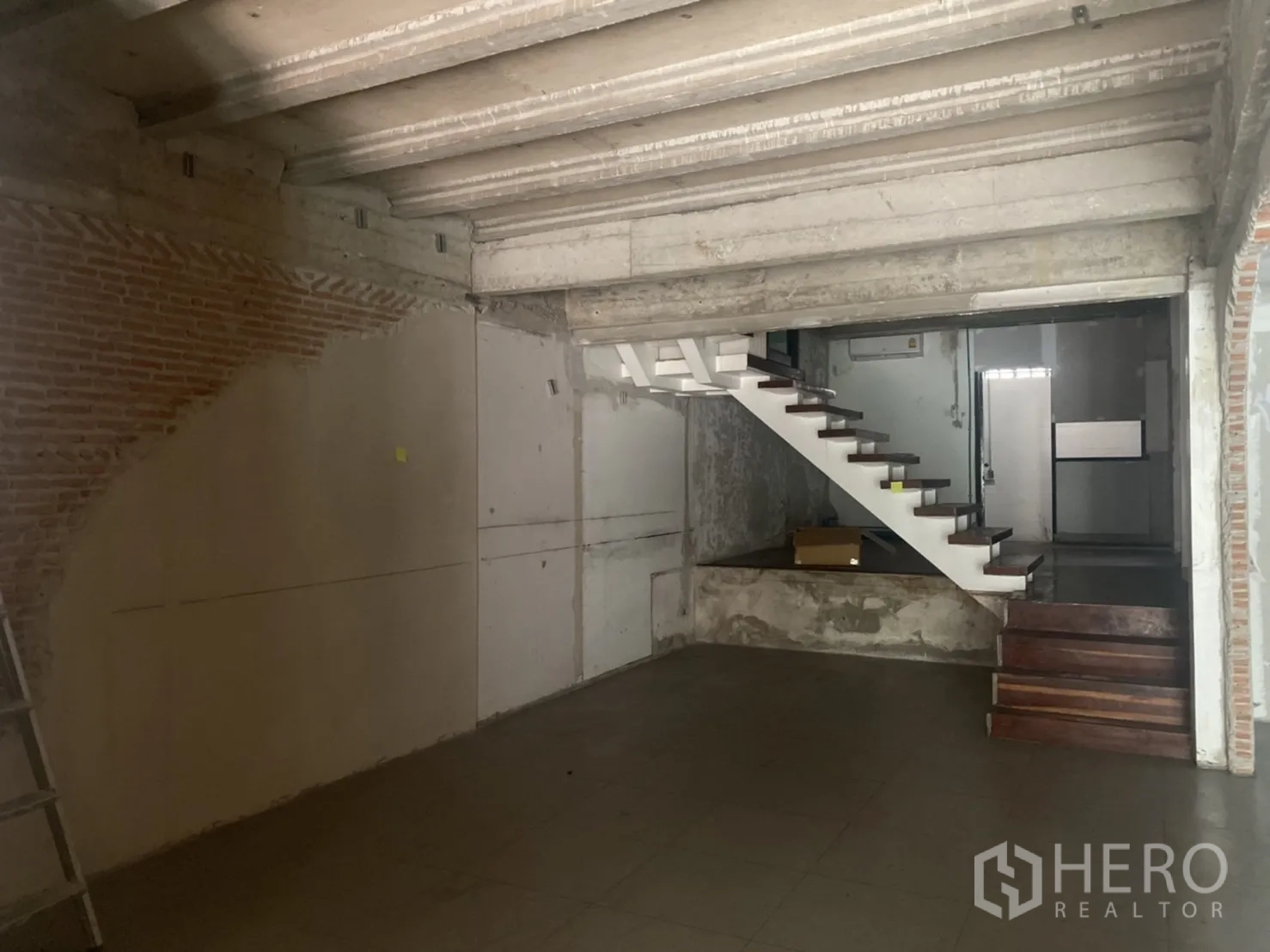 Retail Space for rent in Khlong Toei, Bangkok - Industrial-style retail space with a white floating staircase and concrete ceiling.