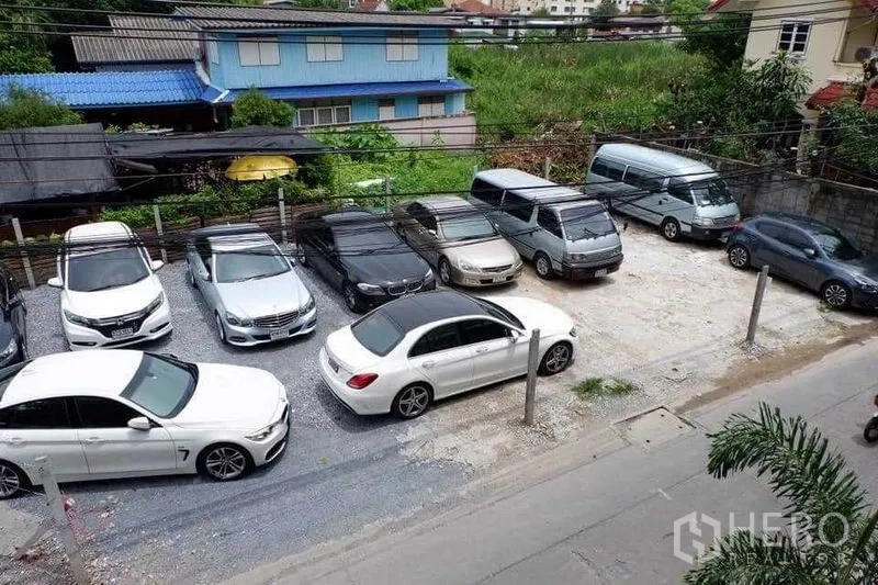 Home Office for rent in Din Daeng, Bangkok - Private gravel parking lot with multiple cars inside a walled compound.