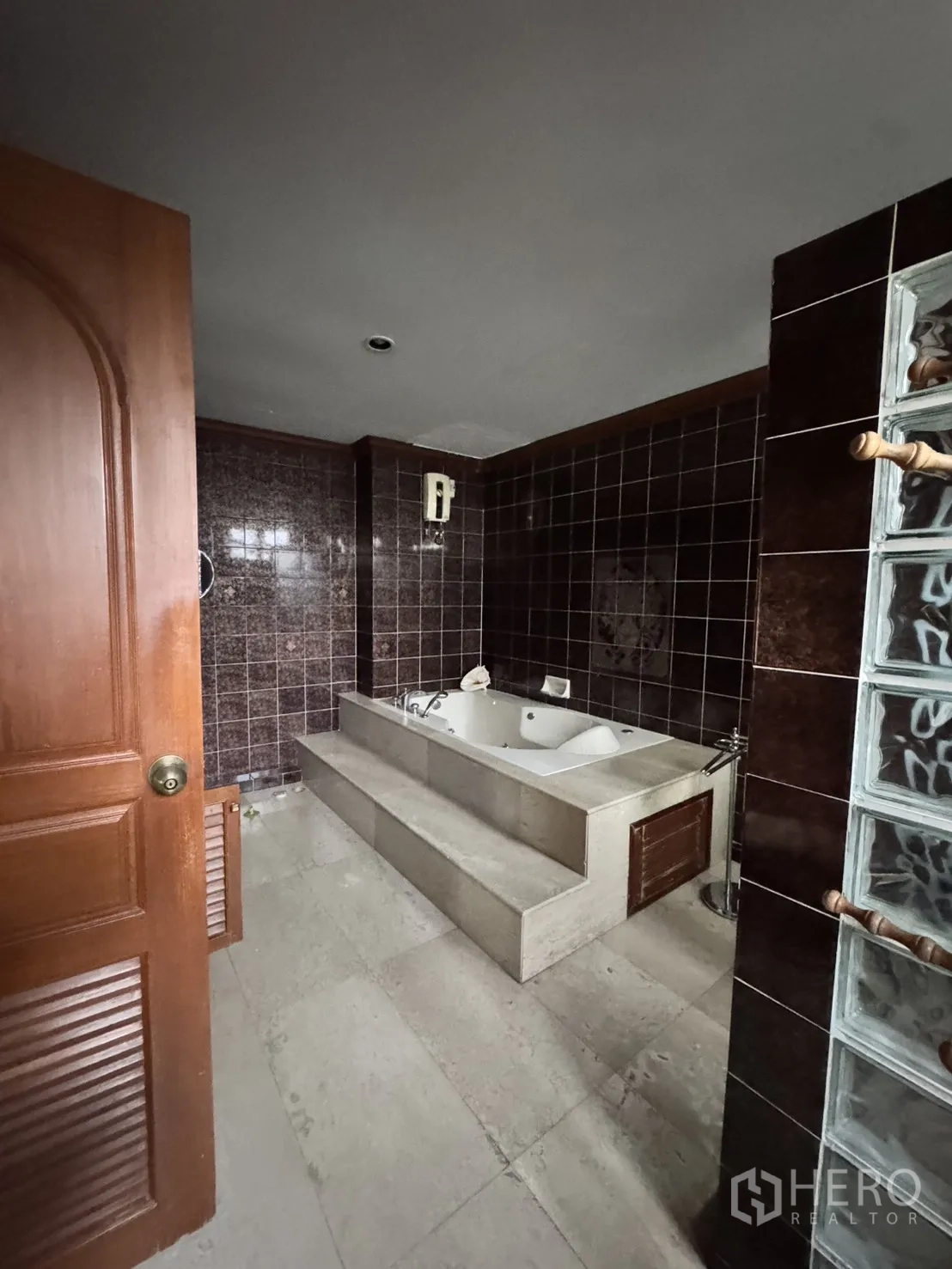 โฮมออฟฟิศ for rent in Watthana, Bangkok - ห้องน้ำผนังกระเบื้องสีน้ำตาล อ่างอาบน้ำยกขั้น และผนังกระจกบล็อก