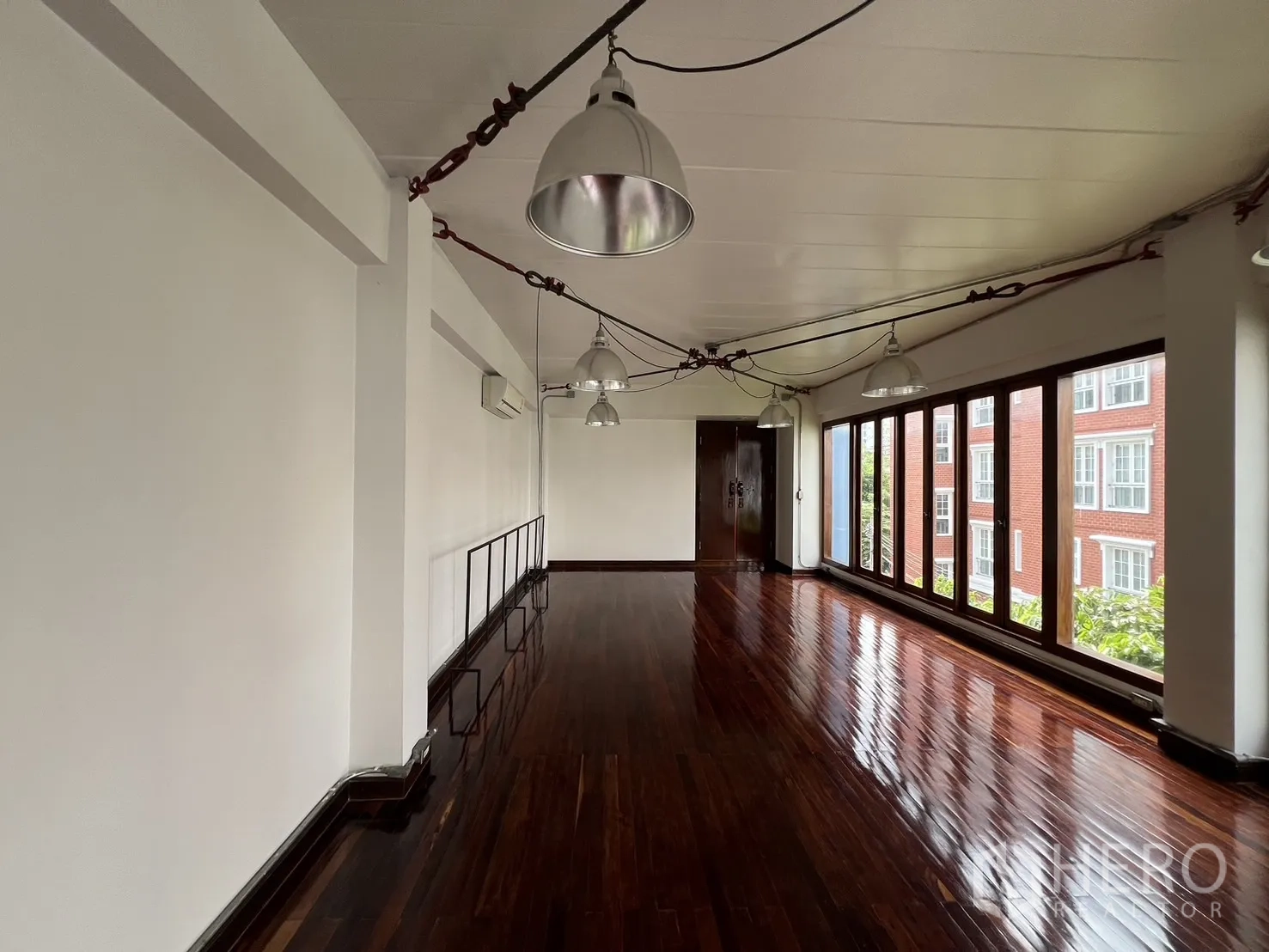 带办公室的家 出租在Watthana, Bangkok - 长条形工作空间，亮泽木地板、一整面窗户与城市景观。