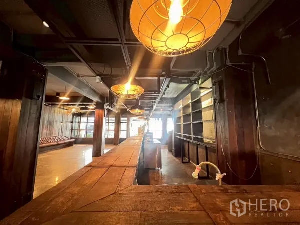 พื้นที่ขายปลีก ให้เช่า - ภายในบรรยากาศอบอุ่นพร้อมบาร์ไม้ยาว โคมไฟห้อย และชั้นวางสไตล์อินดัสเทรียล