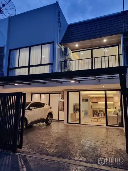 Townhouse for rent or sale - Two-storey townhouse exterior with covered carport and wide sliding doors at dusk.