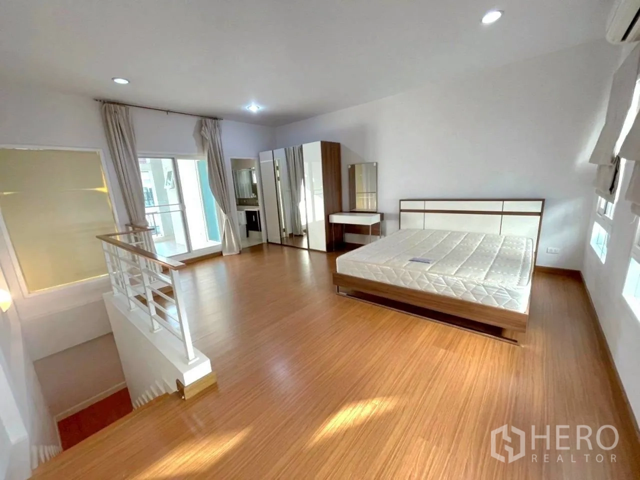 Townhouse for rent in Bang Kho Laem, Bangkok - Expansive upper bedroom with wood floors, wardrobes and access to a balcony.