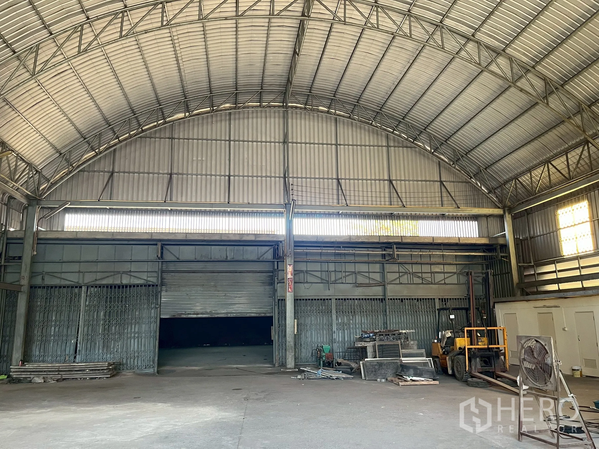Factory for rent in Phra Pradaeng, Samut Prakan - Front wall with three large roller doors under the vaulted roof and equipment nearby.