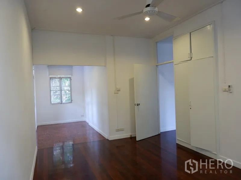 Detached House for rent in Khlong Toei, Bangkok - Bedroom with hardwood floors, built-in wardrobe and a ceiling fan.