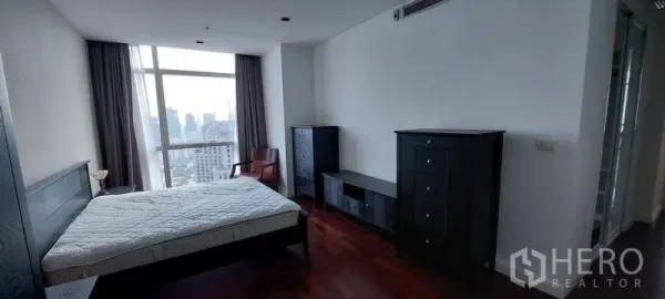 公寓 出租在Pathum Wan, Bangkok - 主卧室可观城市天际线，深色木地板，黑色斗柜与床，位于帕吞旺公寓。