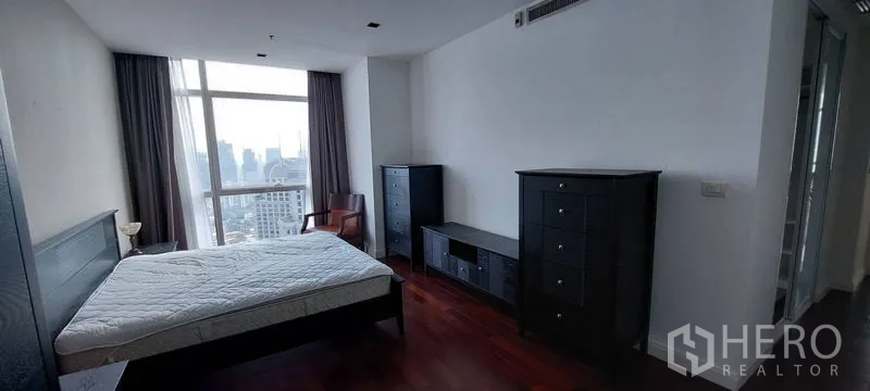 公寓 出租在Pathum Wan, Bangkok - 主卧室可观城市天际线，深色木地板，黑色斗柜与床，位于帕吞旺公寓。