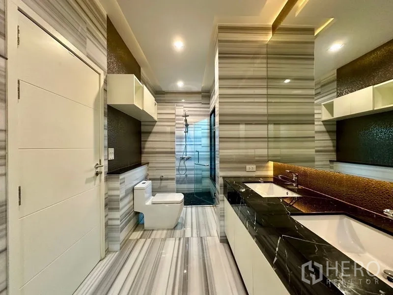 Detached House for rent - Luxury bathroom with striped marble tiles, double vanity and a glass walk-in shower.