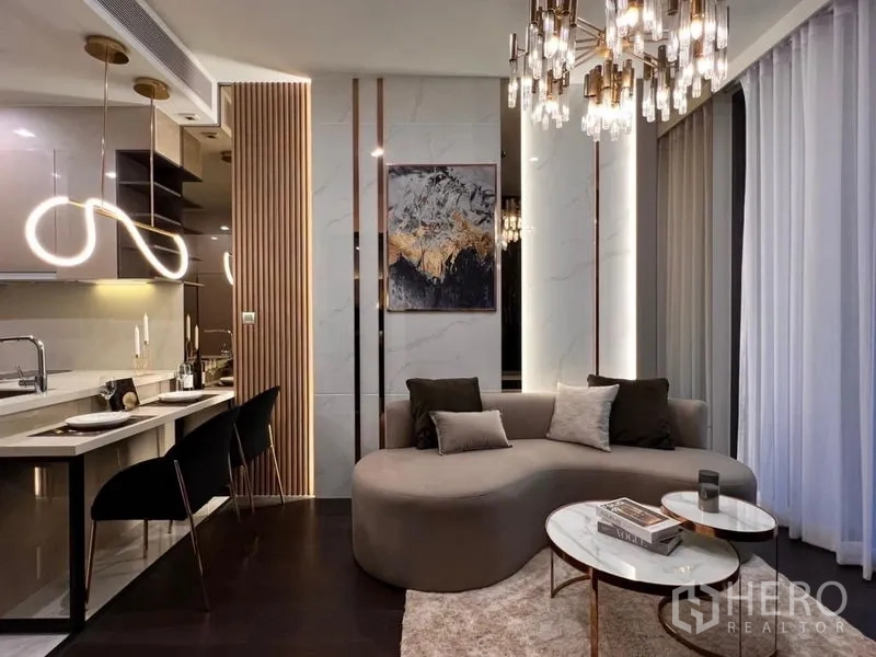 Condominium for rent in Watthana, Bangkok - Contemporary living room with curved sofa, marble accent wall, and illuminated breakfast bar lighting.