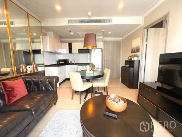 Condominium for rent in Watthana, Bangkok - Open-plan living room with leather sofa, TV, round dining set and fitted kitchen.