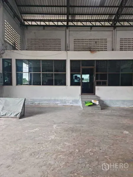 Warehouse for rent in Krathum Baen, Samut Sakhon - Internal office block with large windows inside the warehouse facing a concrete loading area.