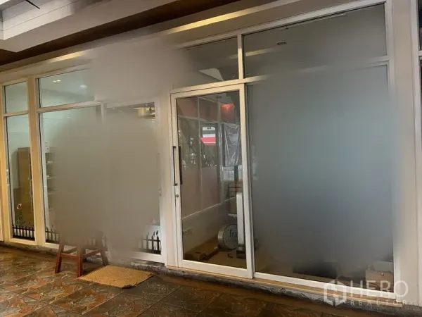 Retail Space for rent in Khlong Toei, Bangkok - Retail unit exterior with large frosted glazing, sliding entrance door, recessed ceiling lights, and stone-tiled floor.