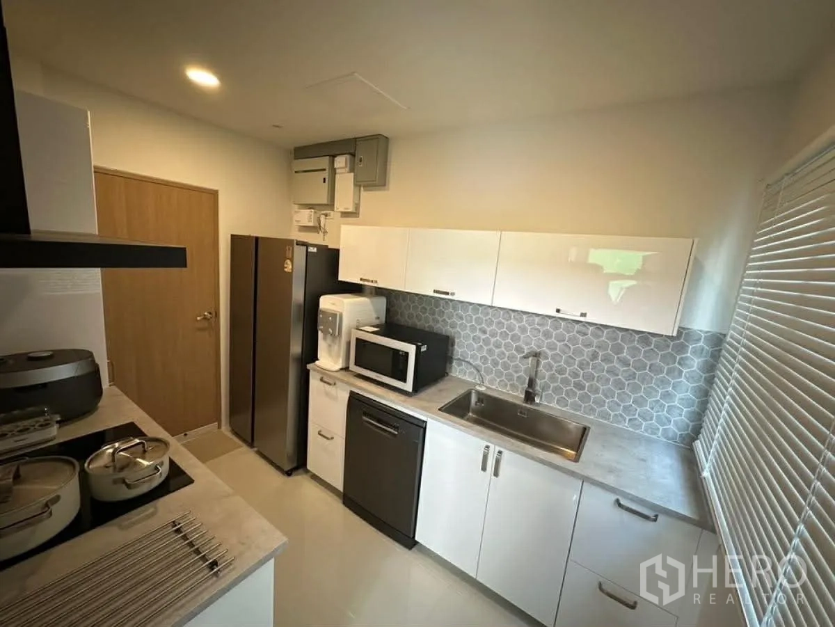 独栋房屋 for rent in Bang Phli, Samut Prakan - 独立现代厨房，白色橱柜、冰箱、微波炉与六角砖防溅墙。