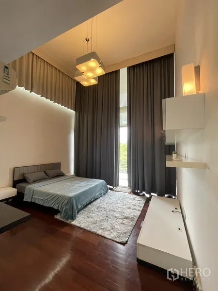 Townhouse for rent or sale in Chatuchak, Bangkok - High-ceiling bedroom with floor-to-ceiling curtains, wood flooring and soft area rug.