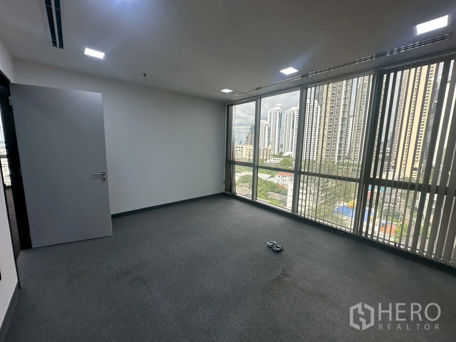 Office Space for rent - Private room with full-height windows, grey carpet and city view.