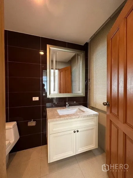独立式住宅 出租或出售在Pak Kret, Nonthaburi - 化妆间/客卫，米色台面与深色特色墙砖。