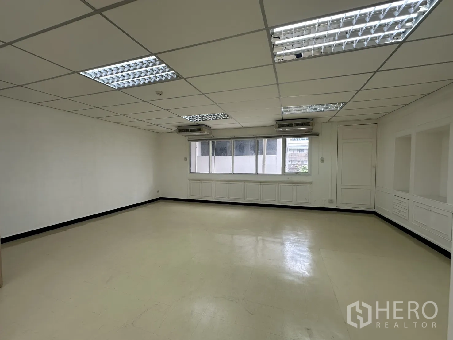 Office Space for rent in Pathum Wan, Bangkok - Bright open-plan office with grid ceiling, fluorescent lights, windows, and built-in cabinets.