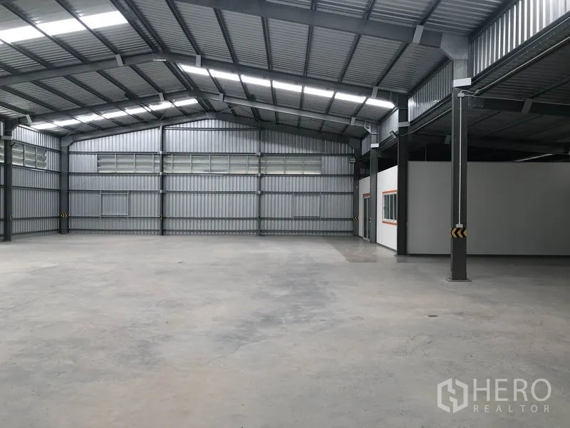 Warehouse for rent in Mueang Nonthaburi, Nonthaburi - Spacious open-plan warehouse interior with steel beams, skylights and smooth concrete flooring.