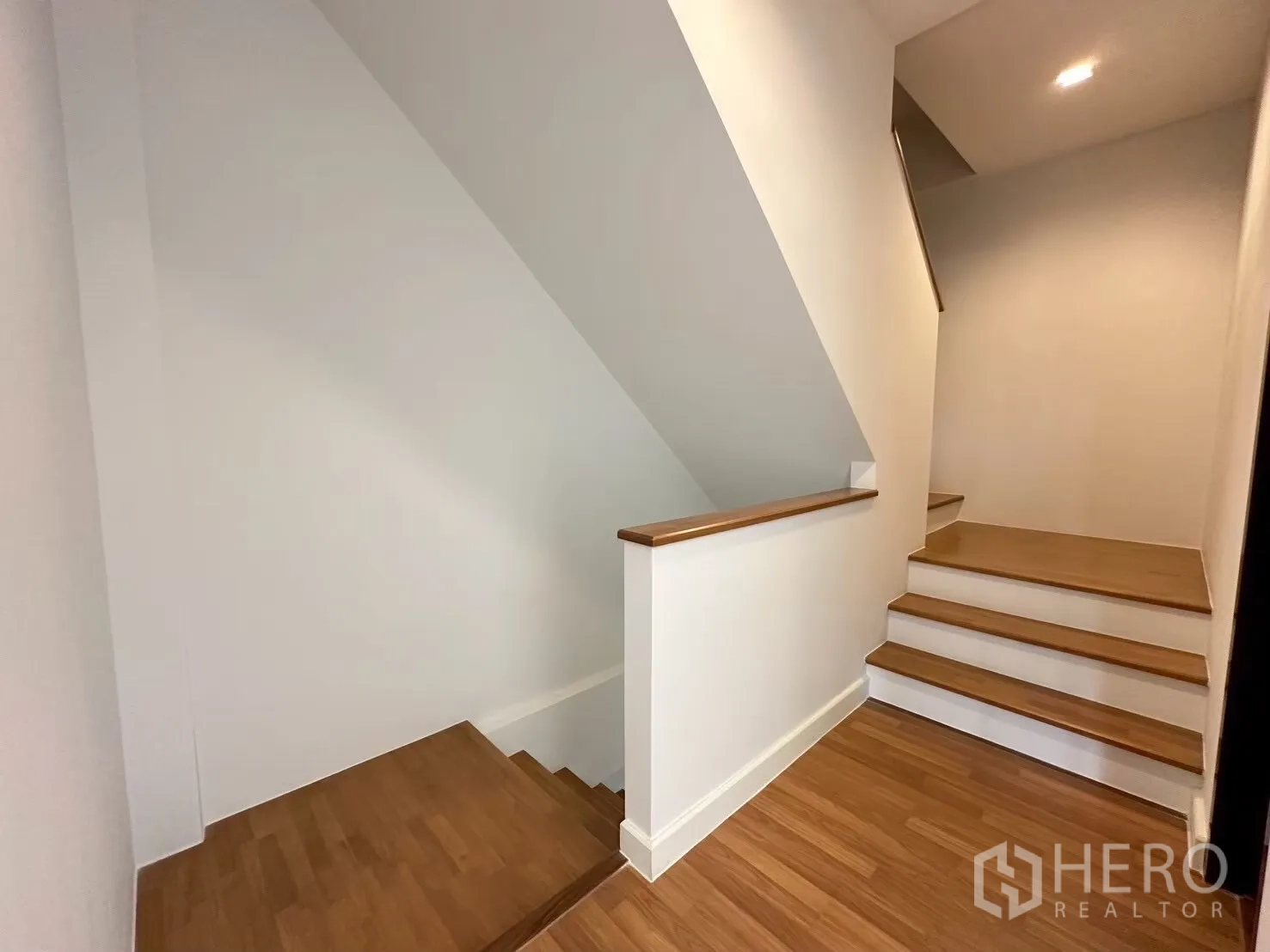 Home Office for rent in Lat Phrao, Bangkok - Clean wooden staircase and landing with white walls and downlights.