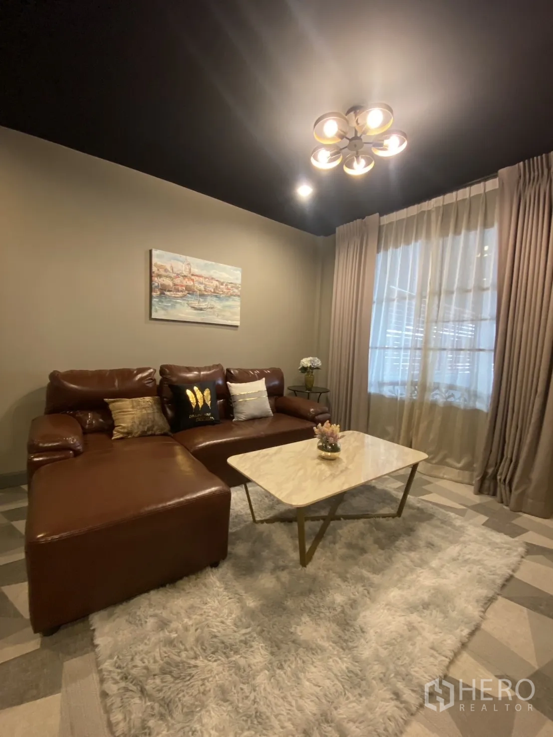 Townhouse for rent in Bang Kapi, Bangkok - Cozy living room with brown leather sectional sofa, marble coffee table and soft rug.