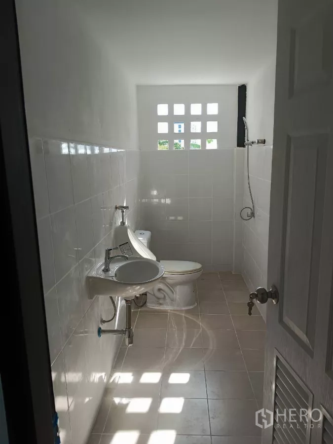 Warehouse for rent in Bang Phli, Samut Prakan - Clean tiled restroom with toilet, sink and shower inside the unit.