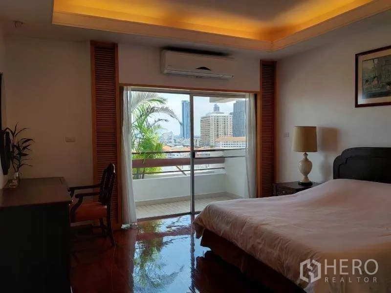 Apartment for rent - Master bedroom opening to a balcony with city skyline view and greenery.