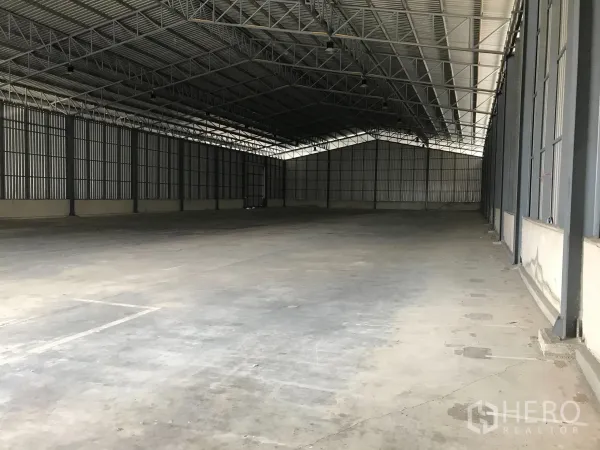 Warehouse for rent in Mueang Samut Prakan, Samut Prakan - Spacious warehouse interior with high steel truss roof and smooth concrete flooring.