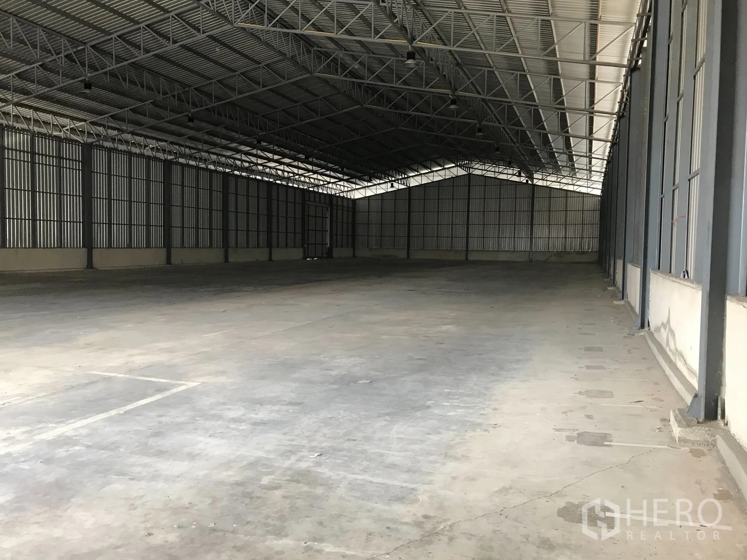Warehouse for rent in Mueang Samut Prakan, Samut Prakan - Spacious warehouse interior with high steel truss roof and smooth concrete flooring.