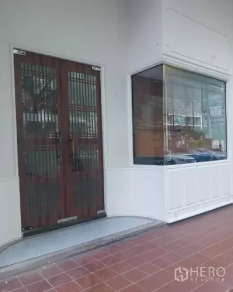 零售空间 出租在Watthana, Bangkok - 入口与转角展示橱窗近景，店面外立面铺有瓷砖。
